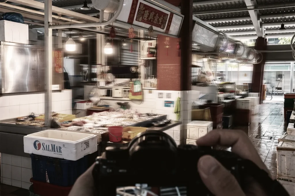 Point-of-view shot of a person holding a camera while photographing a fresh seafood stall at an Asian wet market.