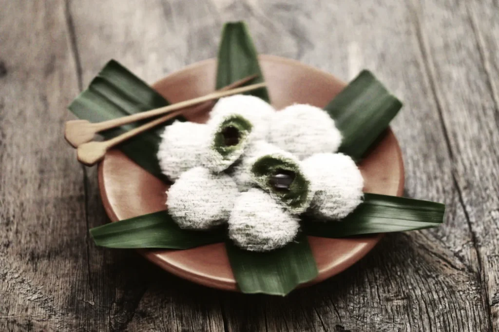 Traditional ondeh‑ondeh coconut rice balls with pandan filling served on banana leaves, highlighting authentic Southeast Asian sweets.