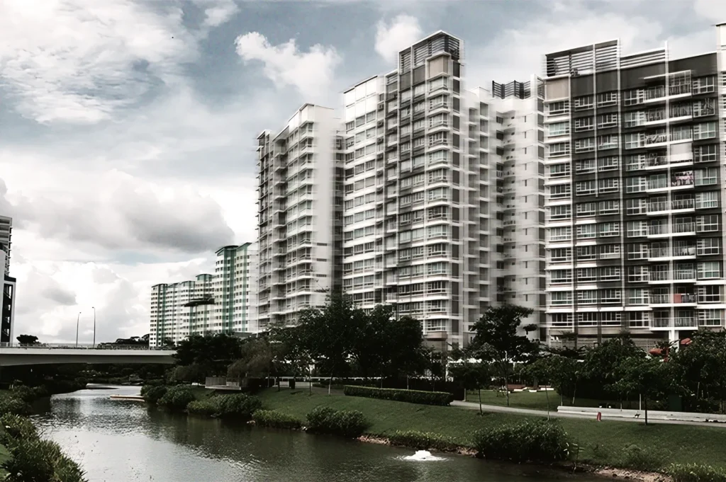 High‑rise residential buildings along a calm river with landscaped greenery, depicting urban living and architecture in Singapore.
